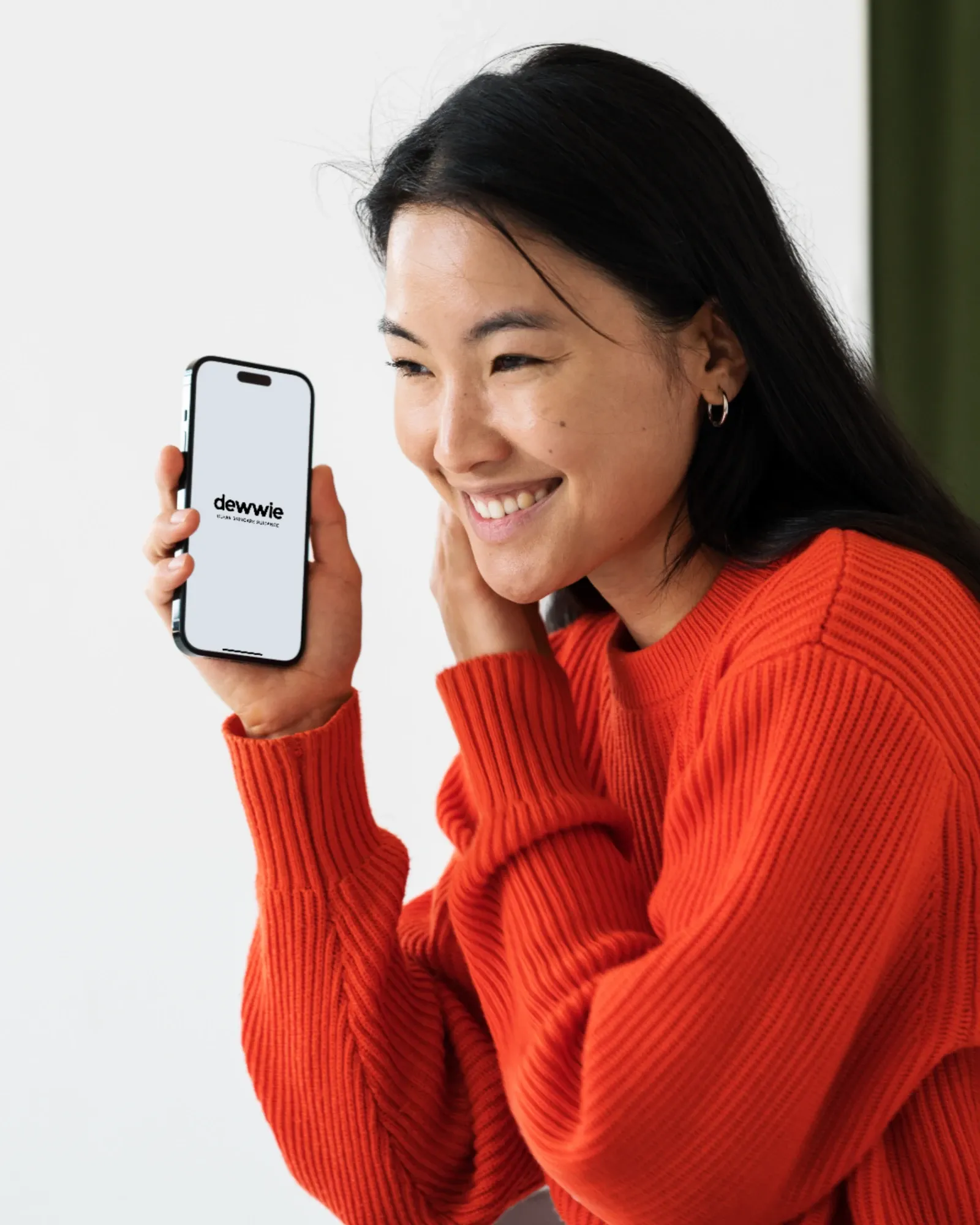 Someone smiling, holding up a phone with dewwie open on it.