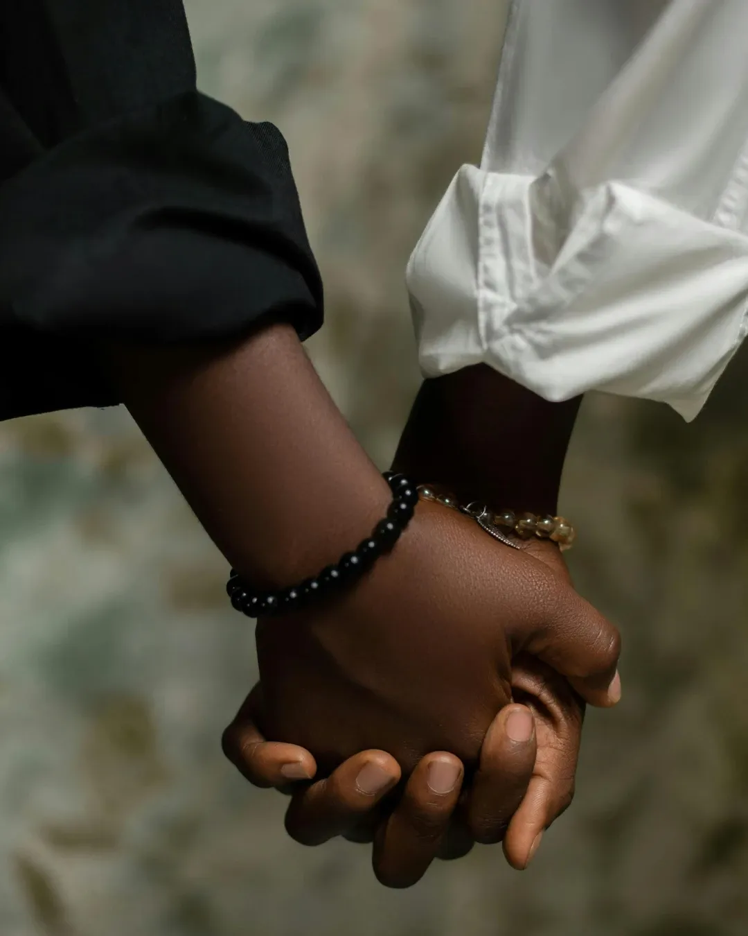 Two people walking side by side, holding hands.